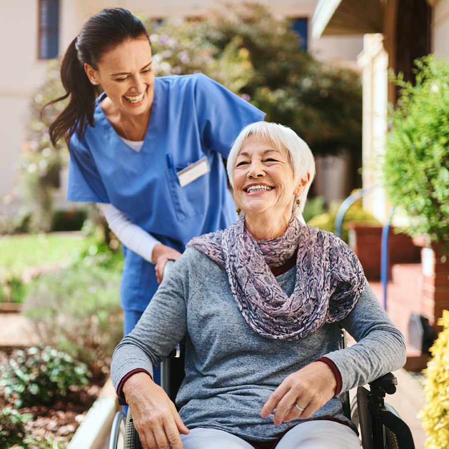 image of a nurse pushing a woman in a wheel chair outside 